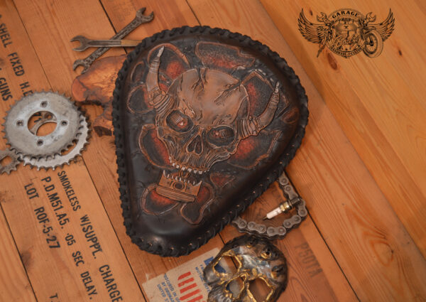 Handmade bobber solo seat with a custom design of a horned skull made out of leather which is hand tooled and laced.