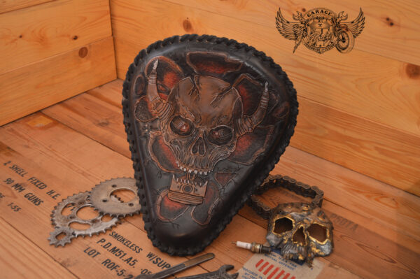 Handmade bobber solo seat with a custom design of a horned skull made out of leather which is hand tooled and laced.