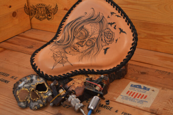 Handmade bobber solo seat with tattooed design in black ink and natural leather background which is laced.