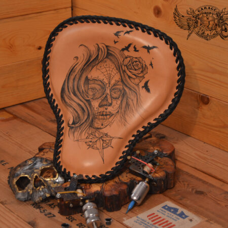 Handmade bobber solo seat with tattooed design in black ink and natural leather background which is laced.