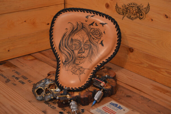 Handmade bobber solo seat with tattooed design in black ink and natural leather background which is laced.