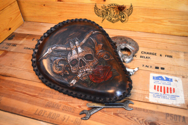 Handmade bobber solo seat with a custom design of a horned skull made out of leather which is hand tooled and laced.