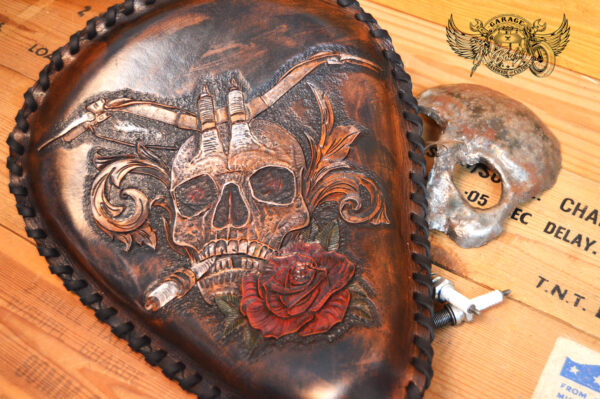 Handmade bobber solo seat with a custom design of a horned skull made out of leather which is hand tooled and laced.